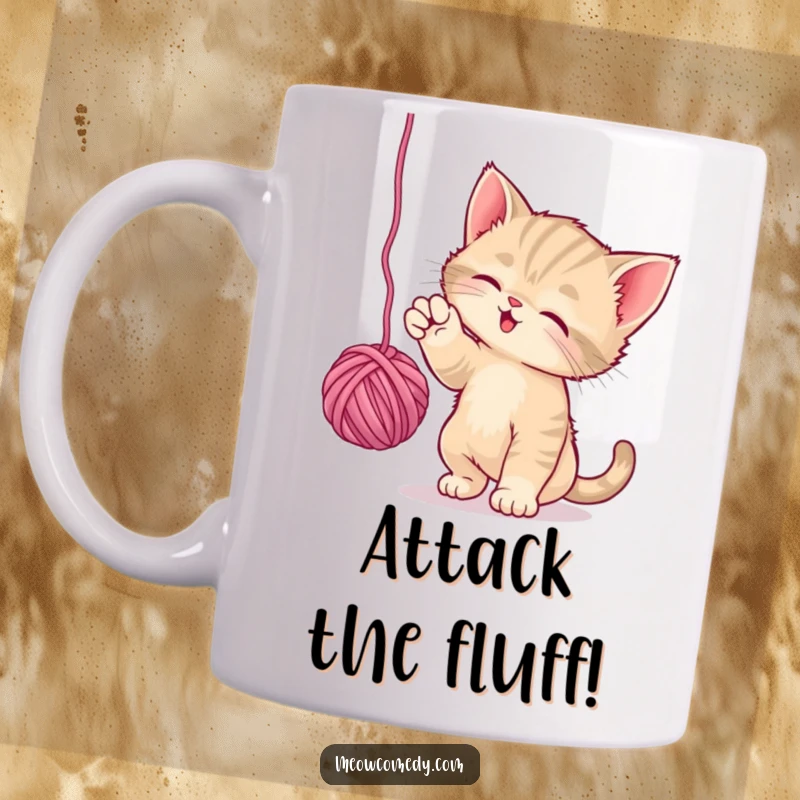 Funny Playful Kitten Mug: A cute kitten energetically bats at a dangling ball of yarn, showcasing playful feline antics.