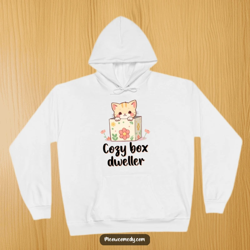 Funny kawaii cat peeking from inside a whimsical, decorated box, a cozy and enchanting scene on a comfortable hoodie.